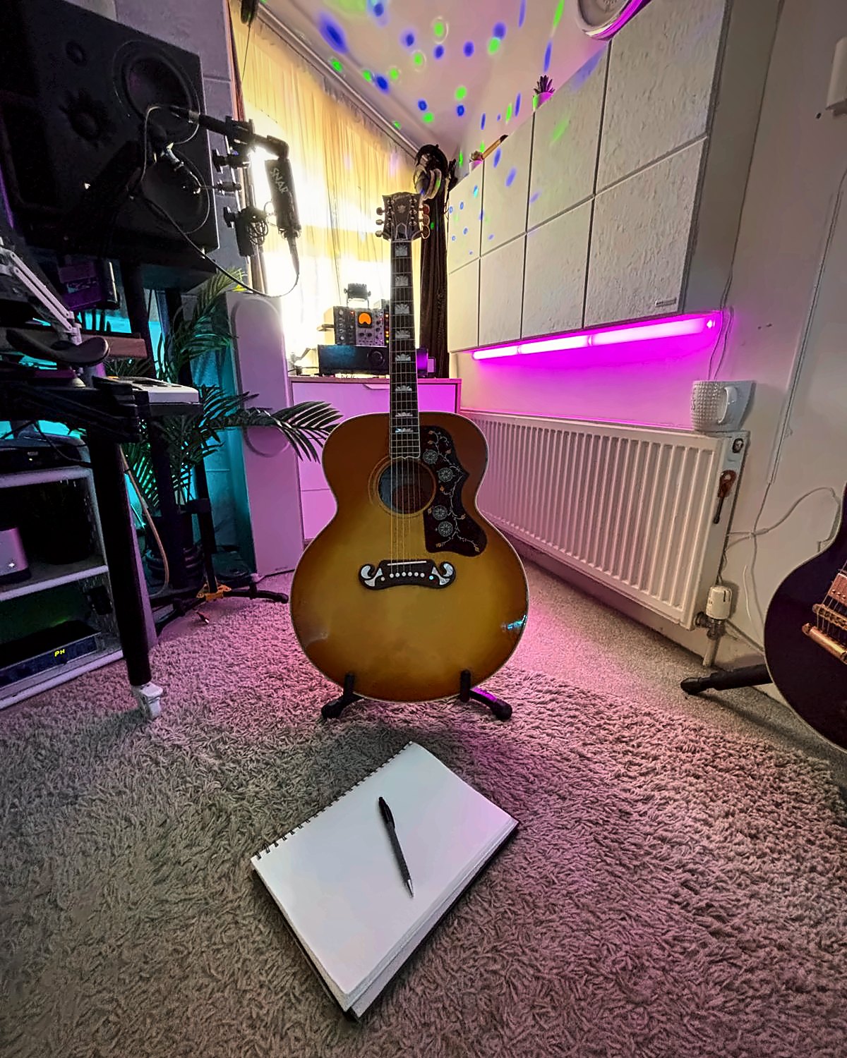 A Gibson acoustic guitar and an open notebook in the Melody Matters writing room